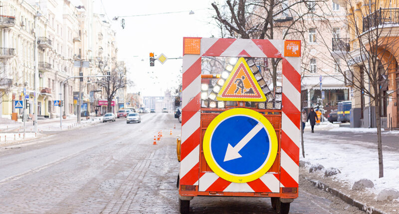 Señales de advertencia sobre las obras de carretera en el lado de una carretera nevada en una calle de la ciudad