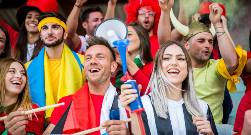 Los aficionados al fútbol en el estadio - Los aficionados al fútbol se divierten y mirando partido de fútbol